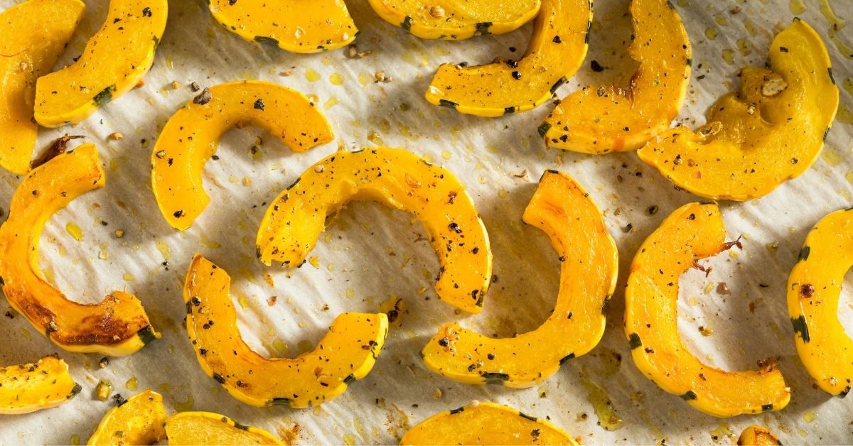 roasted delicata squash black pepper flakes white parchment background