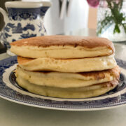 stack of four kamut pancakes on blue and white plate pink flour in the background