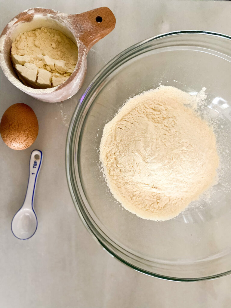 Kamut® Flour Pancake ingredients wooden measuring cup filled with Kamut® flour, brown egg, kamut flour in bowl. 