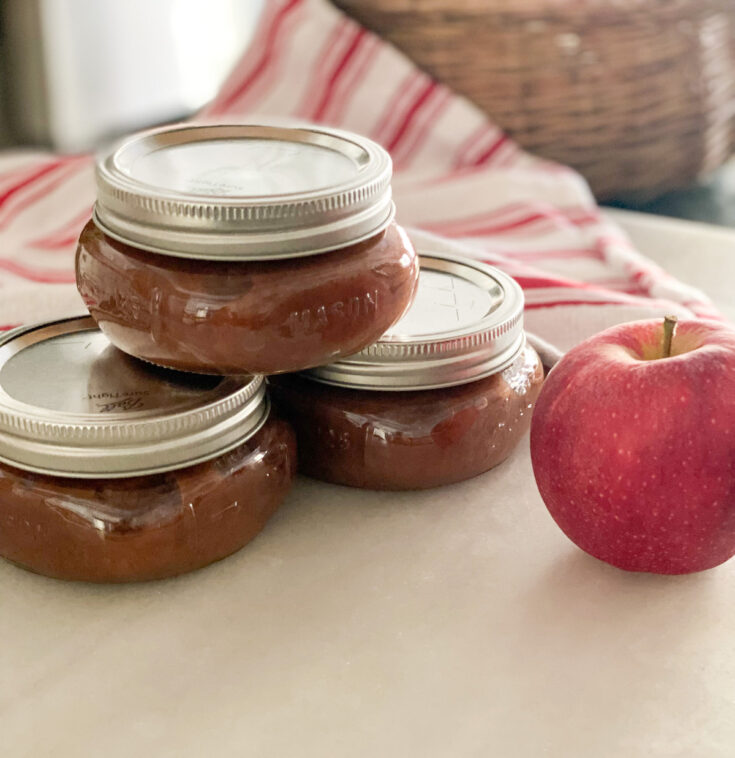 three jars of sugar free apple butter small square mason jars red and white towel in the background red gala apple in the foreground