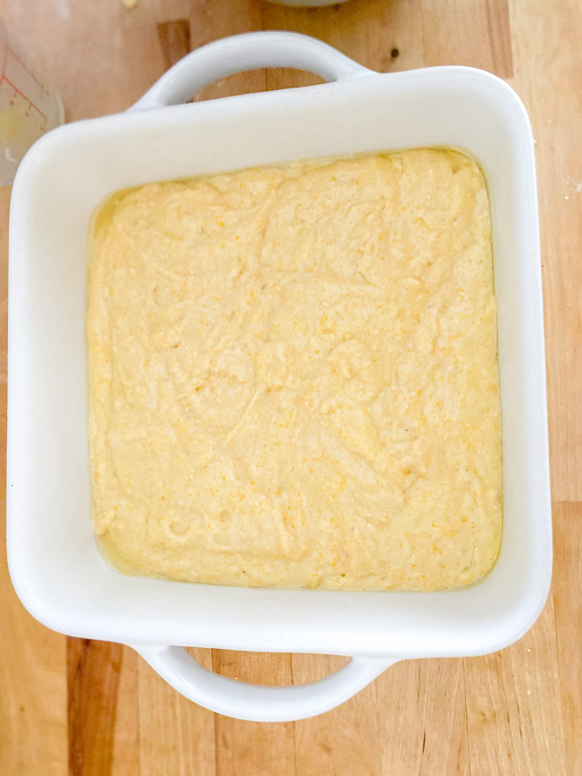 yellow cornbread mixture in a white baking dish 