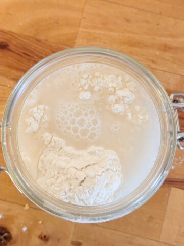 flour and water in a glass jar wood counter background