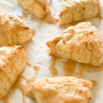 six vanilla bean sourdough scones drizzled with vanilla bean glaze on white partchment paper