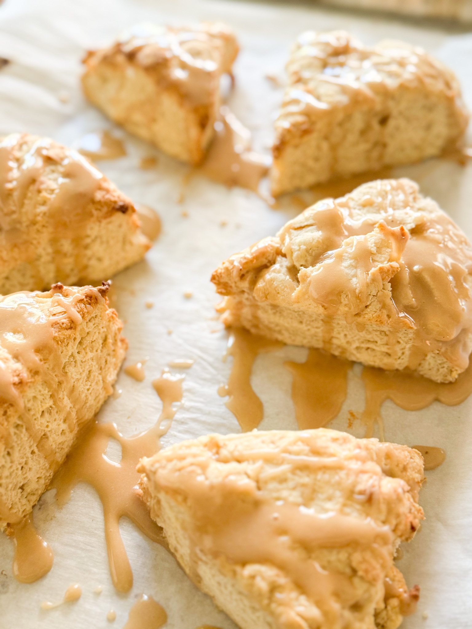 six sourdough vanilla scones on white parchment drizzled with vanilla glaze