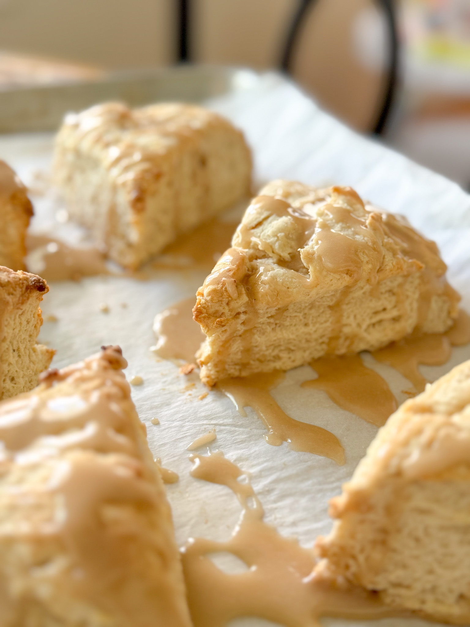 several sourdough scones on white parchment drizzled with vanilla bean glaze